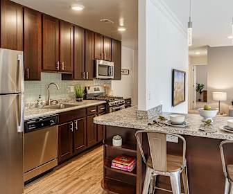 kitchen with a kitchen bar, stainless steel appliances, range oven, dark brown cabinets, light granite-like countertops, pendant lighting, and light hardwood flooring, Merrifield at Dunn Loring Station