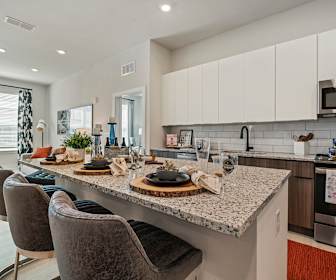 kitchen with a center island, natural light, range oven, stainless steel microwave, white cabinetry, light flooring, and light granite-like countertops, Mirrorton Apartments