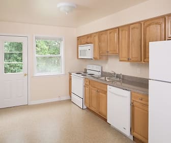kitchen with carpet, natural light, refrigerator, microwave, electric range oven, baseboard radiator, dishwasher, light floors, brown cabinets, and light countertops, Kentwood Village