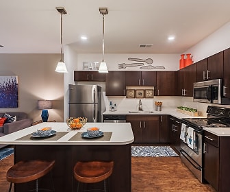 kitchen with a breakfast bar, stainless steel appliances, electric range oven, pendant lighting, dark brown cabinetry, dark floors, and light countertops, The Kane Apartment Homes