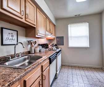 kitchen featuring natural light, range hood, dishwasher, range oven, dark granite-like countertops, light tile flooring, and brown cabinetry, Wilkeswood Apartments