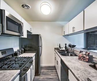 kitchen with gas range oven, dishwasher, microwave, white cabinetry, light granite-like countertops, and dark floors, Mediterranean Village