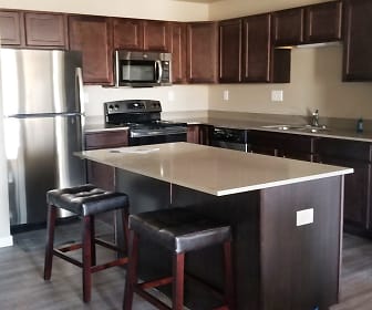 kitchen featuring a kitchen bar, a kitchen island, electric range oven, stainless steel appliances, light countertops, dark brown cabinets, and light hardwood flooring, Rivers Bend Apartment Homes