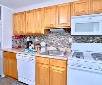 kitchen with washer / dryer, gas range oven, dishwasher, microwave, dark flooring, light countertops, and brown cabinets, Gwynnbrook Townhomes