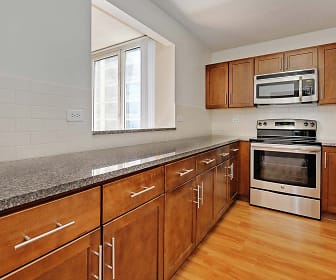 kitchen with natural light, stainless steel microwave, electric range oven, dishwasher, light stone countertops, brown cabinets, and light parquet floors, Hyde Park Tower Apartments
