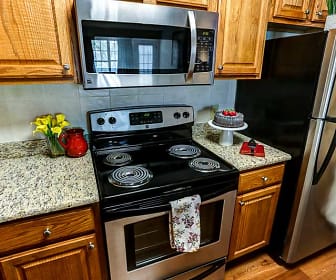 kitchen with electric range oven, stainless steel appliances, light hardwood floors, light granite-like countertops, and brown cabinetry, Windsong Place Apartments
