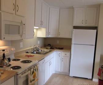 kitchen with refrigerator, dishwasher, electric range oven, microwave, light parquet floors, white cabinets, and light countertops, Lincoln Center Senior Apartments