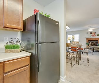 kitchen featuring carpet, a fireplace, refrigerator, light flooring, light countertops, pendant lighting, and brown cabinets, Northbrook Apartments