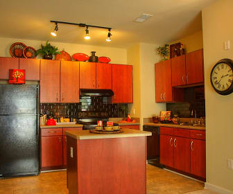 kitchen with a kitchen island, range hood, refrigerator, dishwasher, range oven, light tile floors, brown cabinets, and light countertops, Wesley Stonecrest