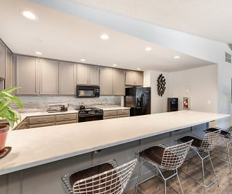 kitchen featuring a breakfast bar area, refrigerator, microwave, range oven, dark flooring, white cabinets, and light countertops, The Renaissance