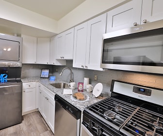 kitchen with stainless steel appliances, light stone countertops, white cabinets, and light parquet floors, Columbia Pointe Apartment Homes