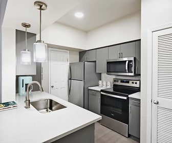 kitchen featuring stainless steel appliances, electric range oven, a kitchen island with sink, light countertops, light parquet floors, pendant lighting, and white cabinets, Camden Huntingdon