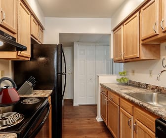 kitchen with refrigerator, extractor fan, dishwasher, dark parquet floors, dark granite-like countertops, and brown cabinetry, Steeplechase Apartments
