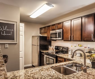 kitchen with refrigerator, electric range oven, stainless steel microwave, light stone countertops, and dark brown cabinetry, River Crossing At Keystone Apartments