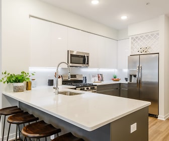 kitchen featuring a breakfast bar, gas range oven, stainless steel appliances, white cabinets, light countertops, and light hardwood flooring, One Ten
