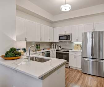 kitchen featuring a kitchen island, stainless steel appliances, range oven, light hardwood floors, pendant lighting, white cabinets, and light countertops, State Thomas Ravello Apartments