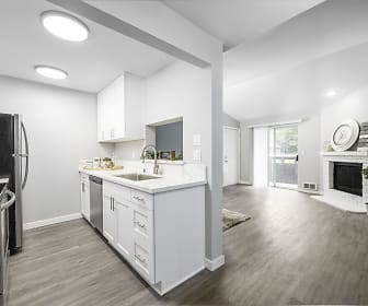 kitchen with natural light, a fireplace, refrigerator, dishwasher, range oven, white cabinetry, light hardwood flooring, and light granite-like countertops, The Mill at Mill Creek