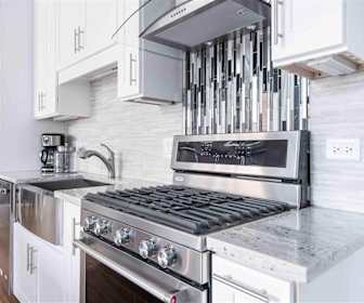 kitchen featuring refrigerator, gas range oven, light floors, and white cabinetry, Wells Place Luxury Apartments