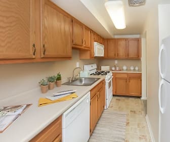 kitchen with gas range oven, refrigerator, dishwasher, microwave, light countertops, light tile floors, and brown cabinetry, Strafford Station Apartment Homes