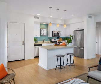 kitchen with a kitchen breakfast bar, range oven, stainless steel refrigerator, dishwasher, microwave, pendant lighting, light countertops, white cabinetry, and light parquet floors, Villas at Playa Vista - Sausalito
