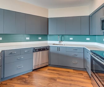 kitchen featuring refrigerator, electric range oven, dishwasher, microwave, light brown cabinetry, light countertops, and light parquet floors, Evanston Place Apartments