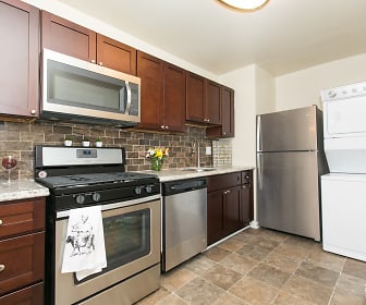 kitchen with washer / dryer, gas range oven, stainless steel appliances, light countertops, light tile floors, and brown cabinetry, Quail Hollow Apartment Homes