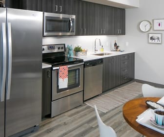 kitchen featuring stainless steel appliances, electric range oven, light hardwood flooring, dark brown cabinets, and light countertops, Sanctuary
