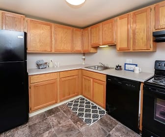 kitchen featuring electric range oven, refrigerator, extractor fan, dishwasher, light countertops, dark tile flooring, and brown cabinetry, Greentree Village Townhomes