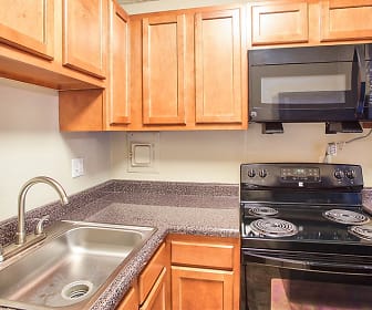 kitchen featuring electric range oven, microwave, dark stone countertops, and brown cabinetry, Solon Club Apartments