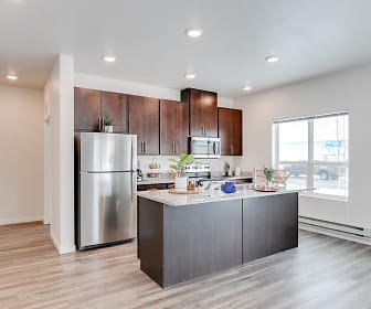 kitchen featuring a center island, natural light, baseboard radiator, stainless steel refrigerator, range oven, microwave, dark brown cabinetry, light stone countertops, and light hardwood flooring, Technology Park Apartments