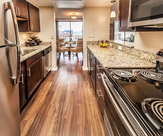 kitchen featuring parquet floors, electric cooktop, stainless steel refrigerator, dishwasher, microwave, pendant lighting, light granite-like countertops, and dark brown cabinets, One Lytle Place Apartments