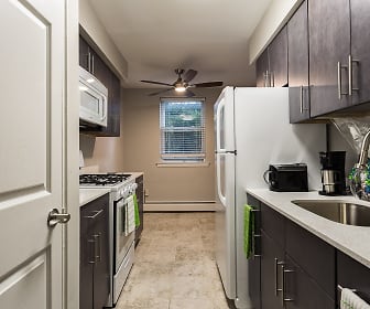 kitchen featuring natural light, a ceiling fan, baseboard radiator, gas range oven, microwave, light tile floors, light granite-like countertops, and dark brown cabinets, 7400 Roosevelt.