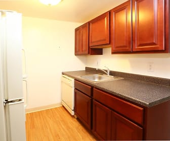 kitchen with refrigerator, dishwasher, brown cabinets, light hardwood floors, and dark stone countertops, The Glen Apartments