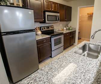kitchen featuring electric range oven, stainless steel appliances, dark brown cabinets, and light stone countertops, Haven at Commons Park