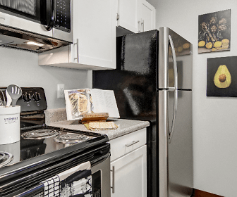 kitchen with electric range oven, refrigerator, dishwasher, stainless steel microwave, white cabinets, and light granite-like countertops, Arbor Creek