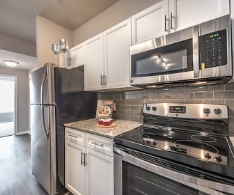 kitchen featuring natural light, stainless steel appliances, electric range oven, white cabinetry, light hardwood flooring, and light granite-like countertops, Olympus 7th Street Station