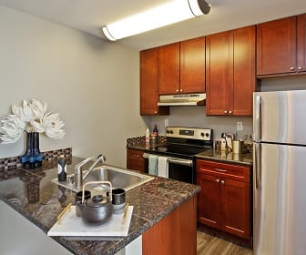 kitchen featuring electric range oven, stainless steel refrigerator, extractor fan, light flooring, dark granite-like countertops, and dark brown cabinets, Oceanaire