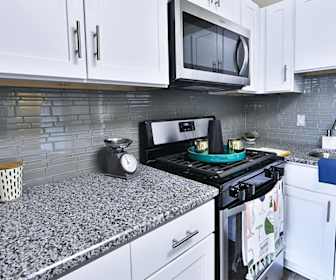 kitchen featuring gas range oven, stainless steel microwave, granite-like countertops, and white cabinetry, Emerald Springs