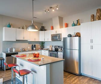 kitchen featuring a center island, a breakfast bar area, electric range oven, stainless steel appliances, white cabinetry, pendant lighting, and dark hardwood floors, 1000 S Broadway Apartments