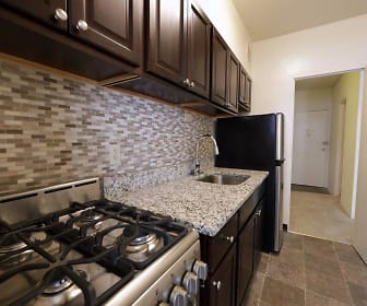 kitchen featuring refrigerator, dark brown cabinetry, light granite-like countertops, and dark tile flooring, The Marylander Apartment Homes