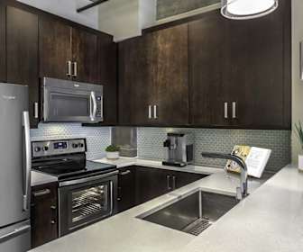 kitchen with electric range oven, stainless steel appliances, dark brown cabinetry, light countertops, and pendant lighting, Camden Cotton Mills