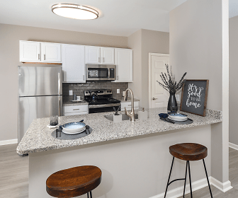 kitchen with a breakfast bar area, stainless steel appliances, white cabinetry, light stone countertops, and light hardwood floors, The Point at Plymouth Meeting