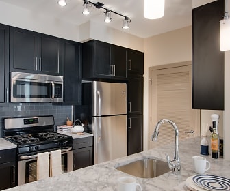 kitchen with gas range oven, stainless steel appliances, light granite-like countertops, dark brown cabinets, and pendant lighting, The Esplanade at National Harbor