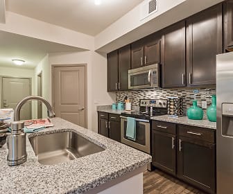 kitchen with a kitchen island, stainless steel appliances, electric range oven, dark parquet floors, pendant lighting, dark brown cabinetry, and light granite-like countertops, Orchid Run Apartments