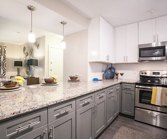 kitchen featuring stainless steel microwave, electric range oven, granite-like countertops, white cabinets, pendant lighting, and light hardwood flooring, Cortland at the Village