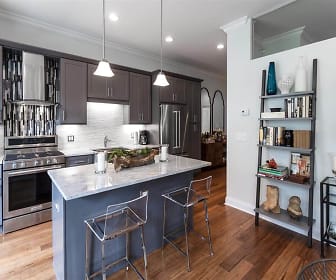 kitchen with a center island, extractor fan, gas range oven, stainless steel refrigerator, dark brown cabinetry, dark parquet floors, light granite-like countertops, and pendant lighting, Wells Place Luxury Apartments