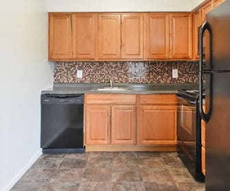 kitchen featuring refrigerator, stainless steel dishwasher, range oven, granite-like countertops, dark tile flooring, and brown cabinetry, William Penn Village Apartment Homes