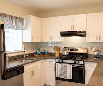 kitchen featuring natural light, exhaust hood, refrigerator, gas range oven, dishwasher, white cabinetry, and light floors, The Ledges
