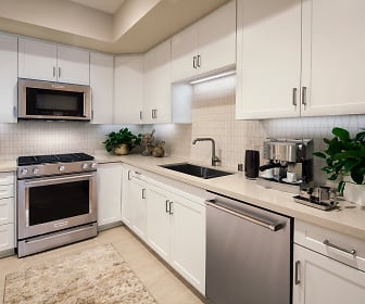 kitchen with gas range oven, stainless steel appliances, light countertops, white cabinetry, and light hardwood flooring, Villas Fashion Island