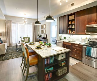 kitchen featuring a kitchen island, natural light, stainless steel microwave, electric range oven, dishwasher, dark brown cabinetry, pendant lighting, light stone countertops, and light hardwood flooring, The Maxwell